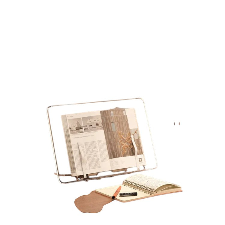 COMFORTH adjustable clear acrylic book stand holding an open book, with a notebook and pen nearby.