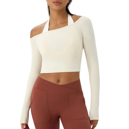 COMFORTH athletic long sleeve crop top in cream with asymmetrical neckline and white halter strap detail.