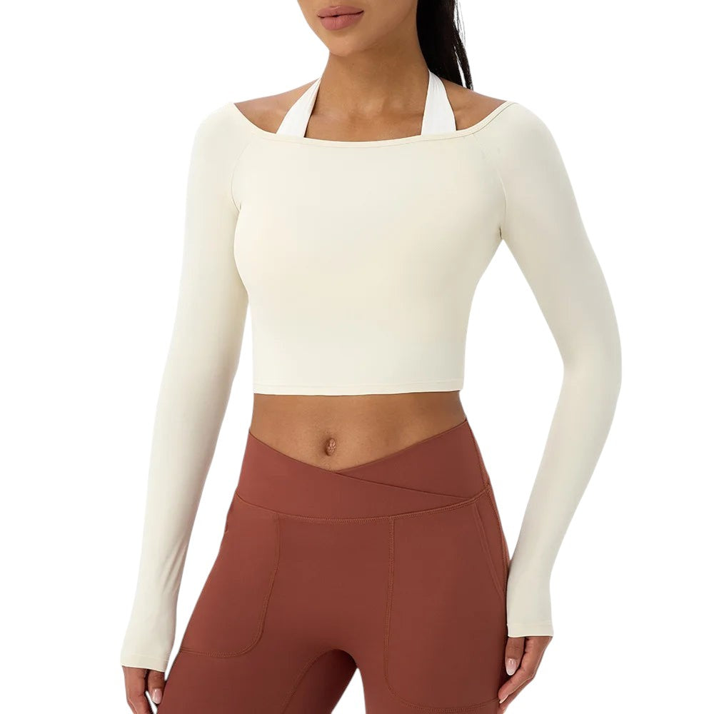 COMFORTH athletic long sleeve crop top in cream, featuring an asymmetrical neckline and made from a nylon-spandex blend.