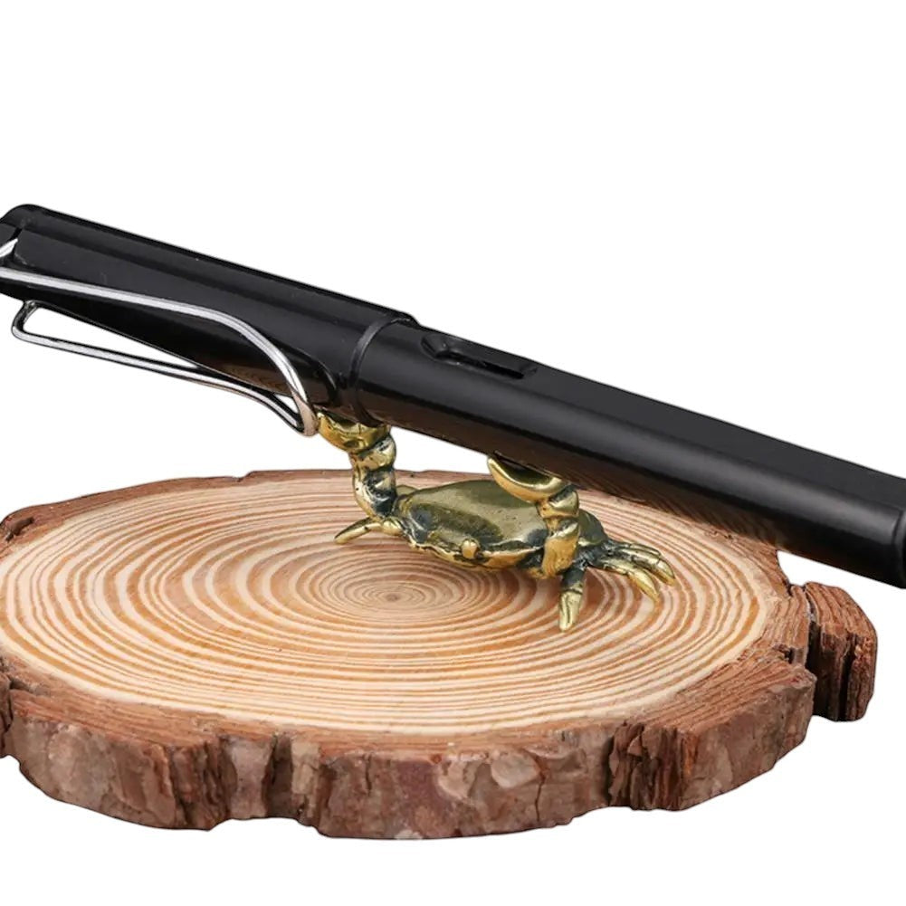 COMFORTH Decorative brass crab pen holder stand on wood slice, holding a black pen.