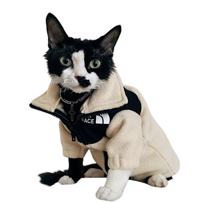 COMFORTH cat wearing a cream and black fleece jacket with a high collar and zipper closure.