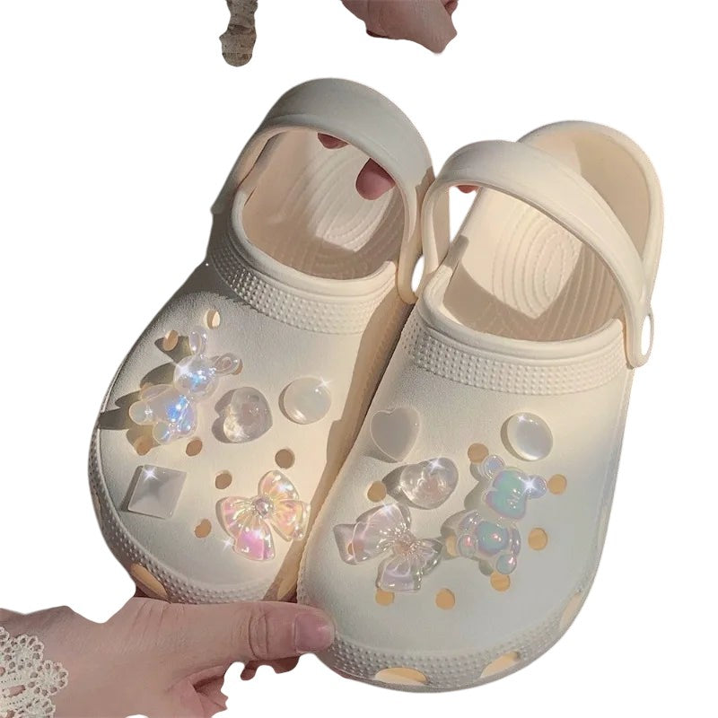 COMFORTH clogs in cream with iridescent teddy bear, heart, and bow charms. Lightweight, waterproof, and comfortable.