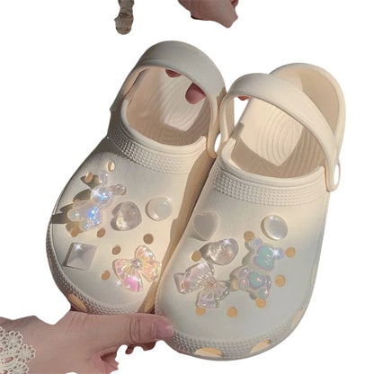 COMFORTH clogs in cream with iridescent teddy bear, heart, and bow charms. Lightweight, waterproof, and comfortable.