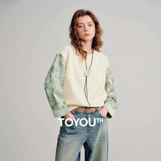 COMFORTH cream cotton blend crew neck sweatshirt with textured sage green contrasting sleeves and ribbed cuffs.