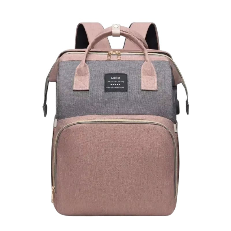 COMFORT Diaper Bag Backpack with Bassinet in dusty rose and grey, water-resistant fabric, multiple compartments, and expandable bassinet.