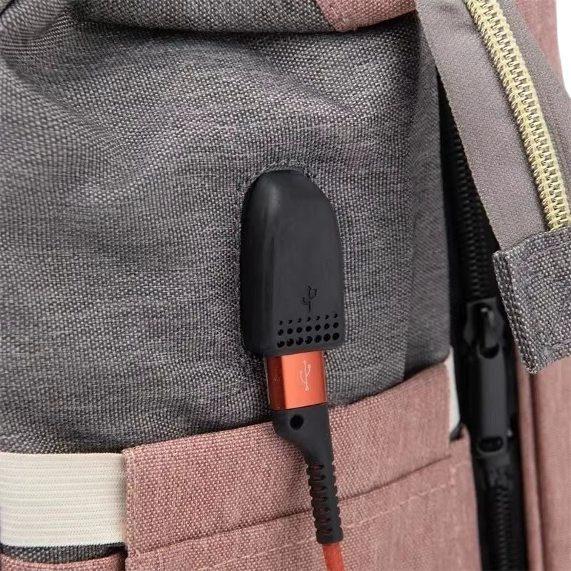 COMFORT diaper bag backpack in grey and pink fabric with external USB port and charging cable.