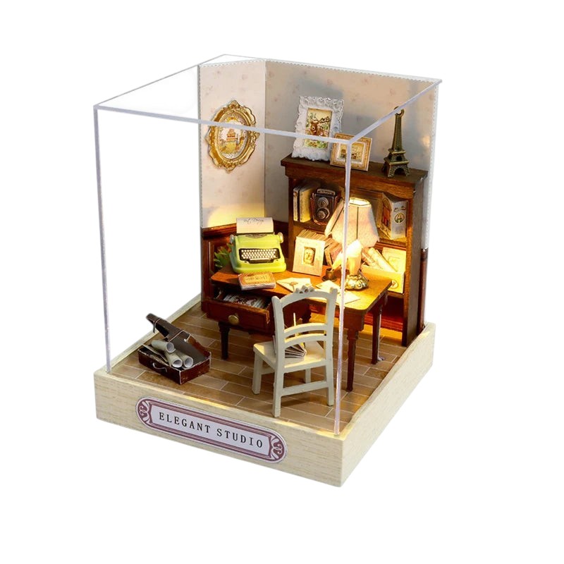 COMFORTH miniature dollhouse building kit featuring a desk with a green typewriter, chair, lamp, and bookshelf. Detailed interior.