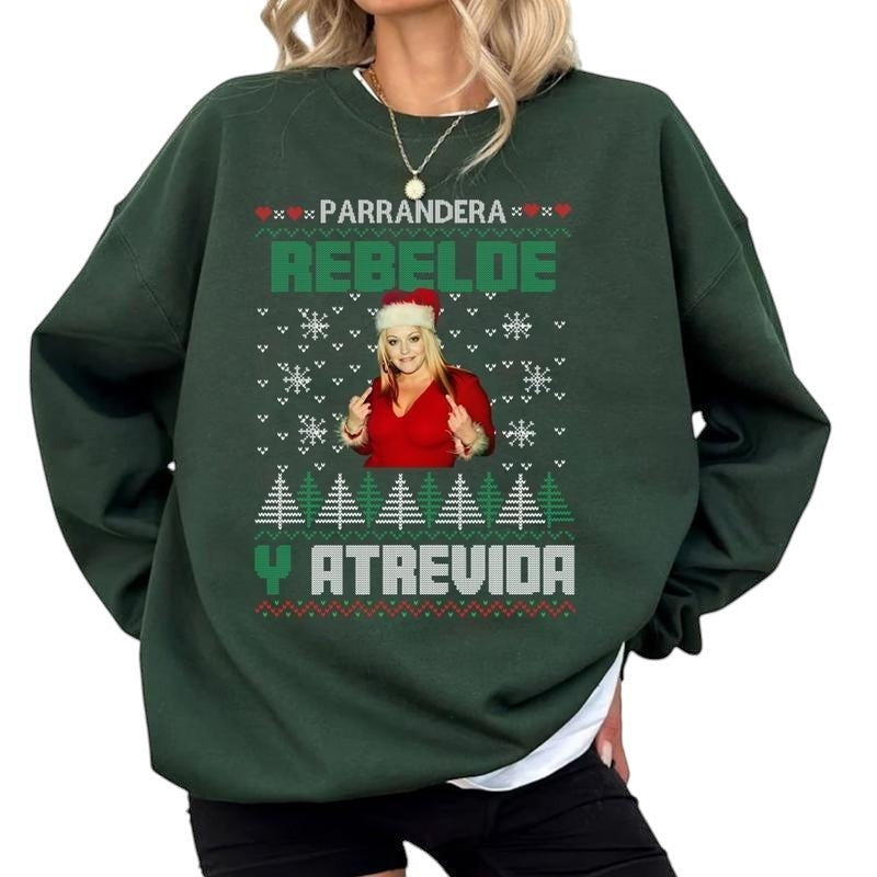 COMFORT green unisex graphic sweatshirt with "Parrandera Rebelde Y Atrevida" text, snowflakes, Christmas trees, and a woman in a Santa hat.