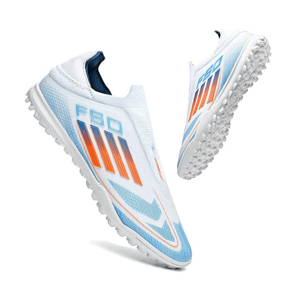 COMFORTH men's white laceless soccer cleats with orange and blue accents. Designed for artificial turf.