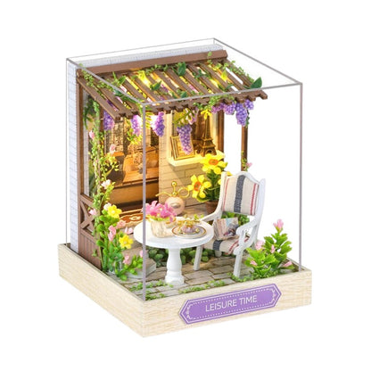 COMFORTH Miniature dollhouse building kit with a patio scene, featuring a table, chair, flowers, and grapevines.