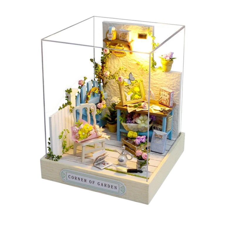 COMFORTH Miniature dollhouse building kit with a garden theme, featuring a blue chair, flowers, and miniature furniture.