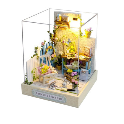 COMFORTH Miniature dollhouse building kit with a garden theme, featuring a blue chair, flowers, and miniature furniture.