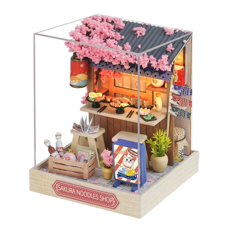 COMFORTH Miniature dollhouse kit of a Japanese noodle shop with cherry blossoms, sushi, and koi flags.