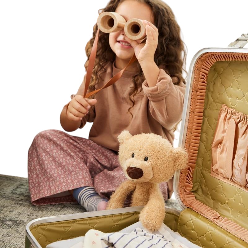 COMFORT plush teddy bear toy in beige, with brown nose and embroidered eyes, sitting next to a child with binoculars.