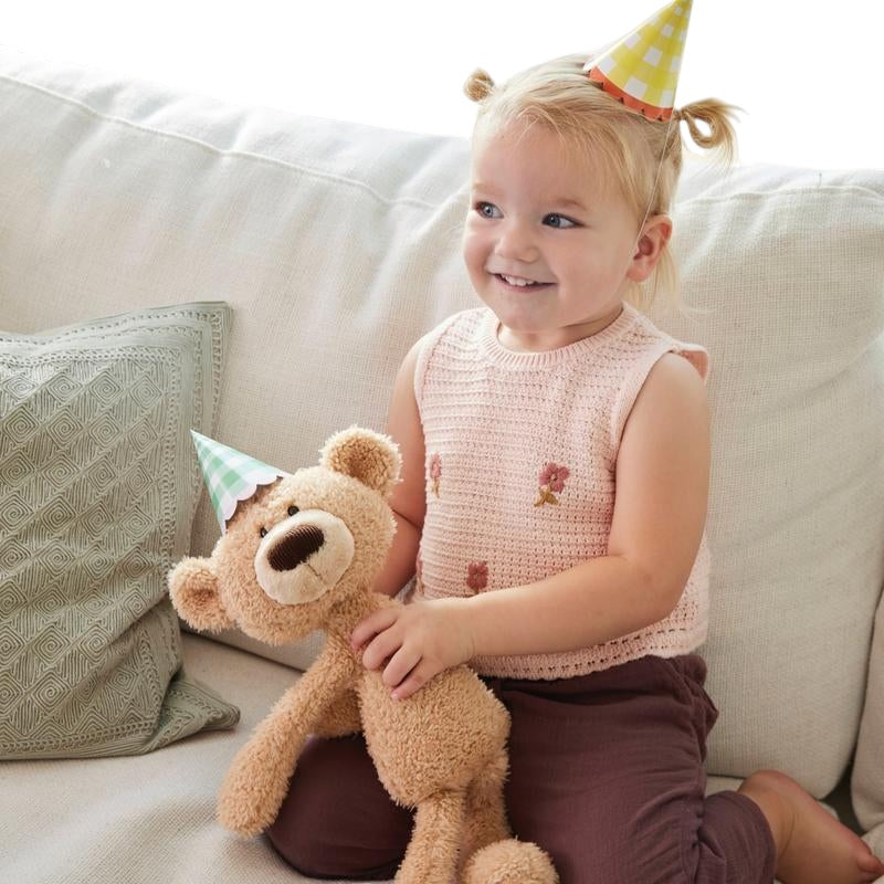 COMFORT plush teddy bear toy in beige with brown nose and embroidered eyes, held by a child.