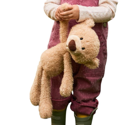 COMFORT plush teddy bear toy in beige with brown nose and embroidered eyes, held by a child.