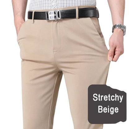 COMFORTH Men's beige stretch dress pants with a flat front and tailored fit. Model's hands in pockets.