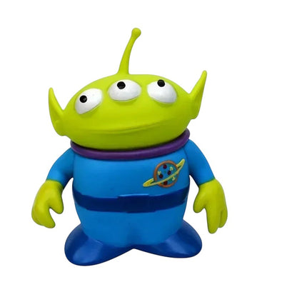 COMFORT Toy Story Alien figure, bright green with three eyes, wearing a blue uniform with Pizza Planet logo. Durable plastic.