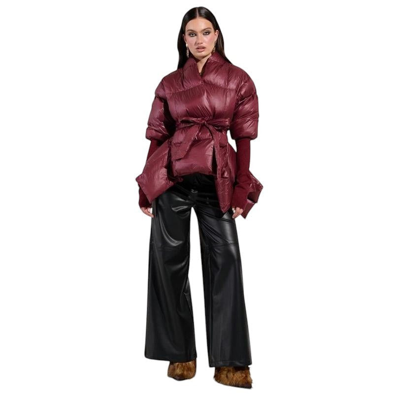 COMFORT Women's burgundy puffer jacket with tie belt, voluminous sleeves, and high collar. Model wears black leather pants.
