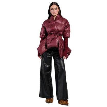 COMFORT Women's burgundy puffer jacket with tie belt, voluminous sleeves, and high collar. Model wears black leather pants.