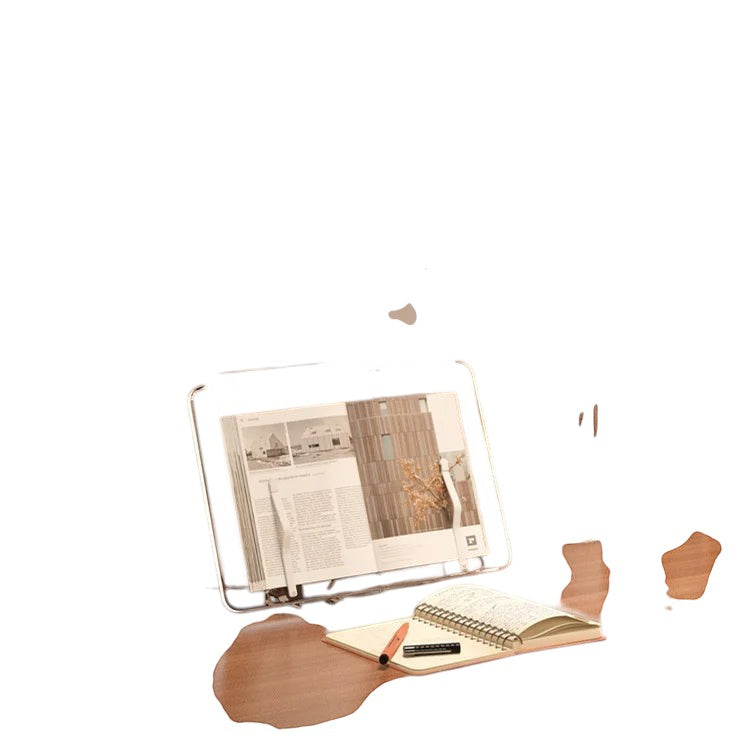 COMFORTH clear acrylic book stand holding an open book, with a notebook and pen beside it. Adjustable for hands-free reading.