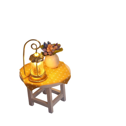 COMFORTH miniature dollhouse table with yellow polka dot cloth, lit lantern, and potted plant.