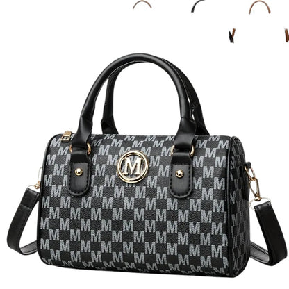 COMFORTH Monogram barrel handbag with shoulder strap, black and grey monogram print, gold M emblem, top handles, and detachable strap.