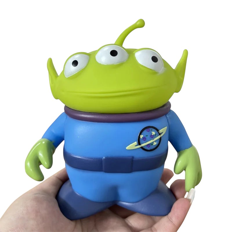 COMFORTH Toy Story Alien figure, green head, three eyes, blue uniform with Pizza Planet logo, articulated arms and head.