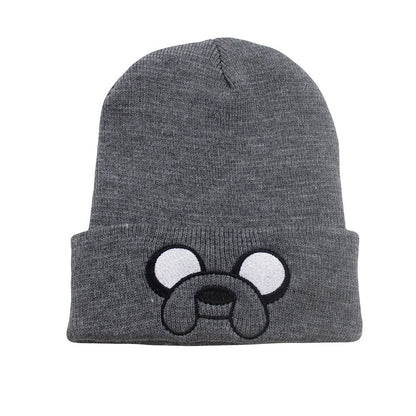 COMFORTHere grey knit beanie hat with embroidered Jake the Dog face from Adventure Time. Features white eyes and black snout.