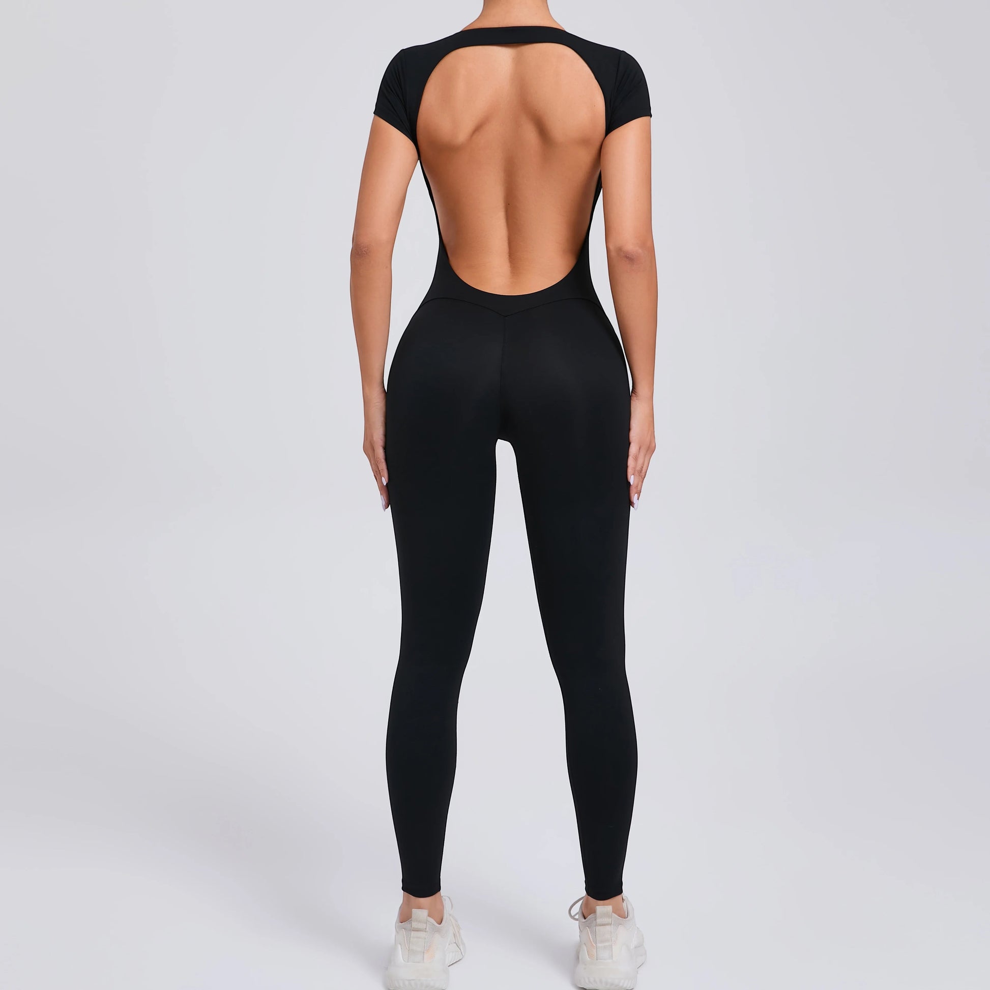 COMFORTHere black short sleeve full length activewear bodysuit with open back and v-shaped waistline.