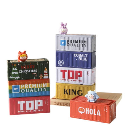 COMFORTHere decorative storage containers resemble shipping containers with figurines. Stacked boxes in red, yellow, blue, and white feature text like "TOP" and "PREMIUM QUALITY".
