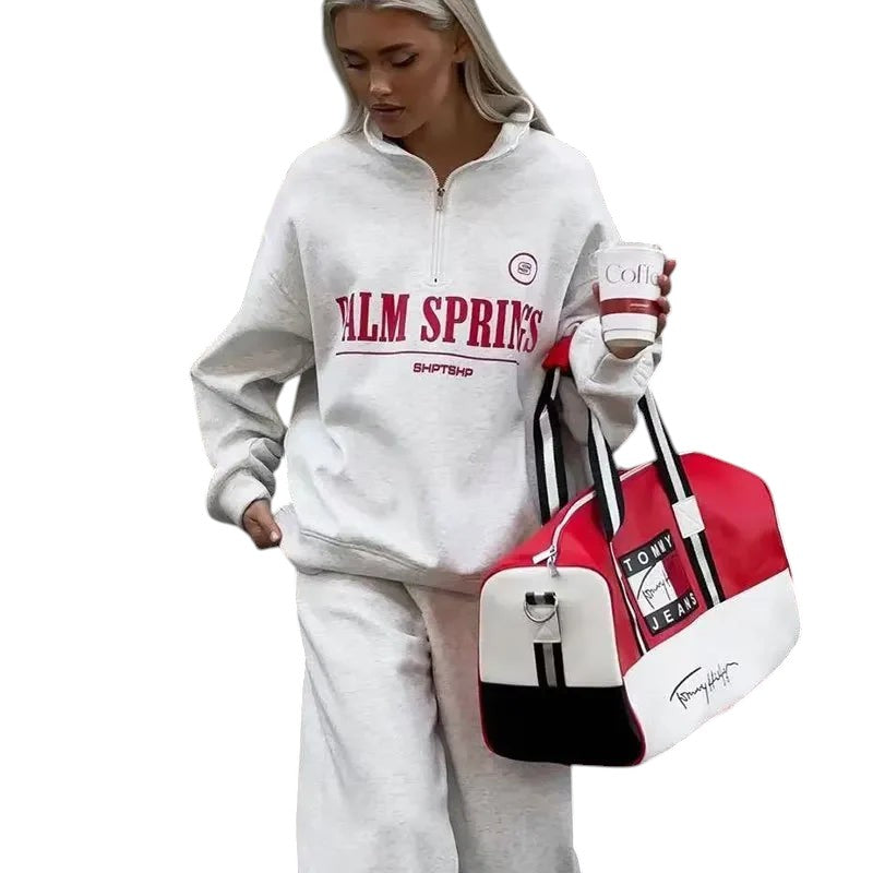 COMFORTHere grey cotton blend quarter zip sweatshirt with "PALM SPRINGS" graphic on chest. Model holding coffee.