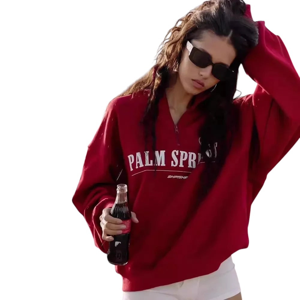 COMFORTHere red cotton blend quarter zip sweatshirt with "PALM SPRINGS" graphic on chest. Model wears sunglasses.