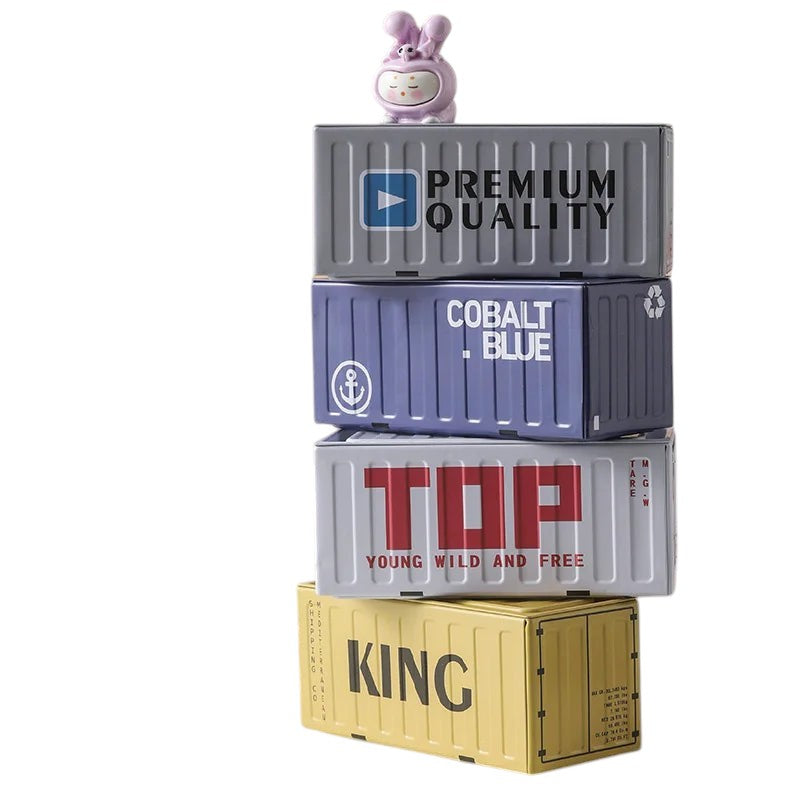 COMFORTHere decorative storage containers designed as shipping containers with figurines. Stacked in grey, blue, white, and yellow.