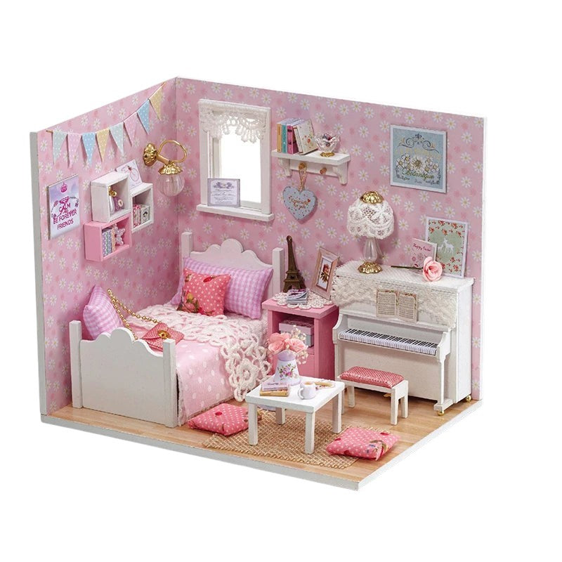 COMFORTS miniature dollhouse building kit featuring a pink bedroom with a white bed, piano, and tiny furniture. Includes decorative details.